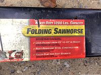 Close-up of label showing 1200 lbs capacity, adjustable leg height from 25 to 40 inches, rust-resistant steel, and fold flat for storage