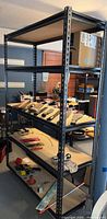 Full view of metal shelving unit with four shelves and various items placed on shelves.