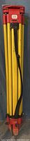 Full view of the folded GST05 tripod stand with yellow legs and red fittings, featuring attached black carrying strap.