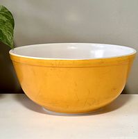 Front view of large orange Pyrex bowl showing exterior paint wear and orange color.