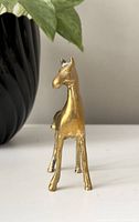 Front view of small brass horse figure showing patina and wear