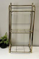 Full view of vintage brass toned metal towel rack showing overall design with three levels for storage and hanging.