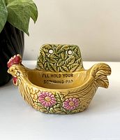 Front view of ceramic rooster scouring pad holder showing text inside and floral pattern