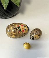 Three vintage hand-painted wooden nesting eggs displayed together showing front face and floral details.