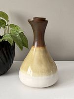 Front and side views of the vintage pottery decanter showing its shape, glaze colors, and lid.