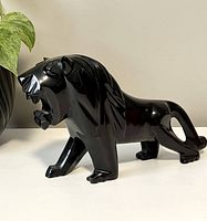 Left-front angle view of the black soapstone lion statue showcasing mane details and open mouth.