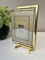 Front view of the solid brass vintage rotating picture frame on its stand with a placeholder insert showing size and branding.