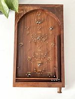 Front view of vintage wooden pinball game showing score markings and some of the 11 included metal pinballs on playing field.