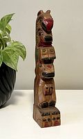 Front view of the vintage wooden totem pole carving showing painted facial features and detailing.