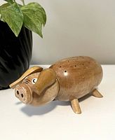 Front angled view of wooden piglet toothpick holder showing facial details and legs