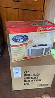 Photo showing a Honeywell Enviracaire Platinum Air Purifier Model 16200 box along with a plain cardboard box labeled with model and brand information.