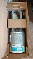 Top view of air purifier inside original cardboard packaging showing unit and protective inserts
