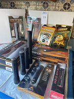 Overall assortment of new-in-box flashlights and headlamps at back with four loose used flashlights in front
