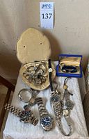 Group of twelve watches arranged on table with one watch case open