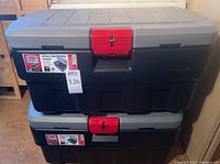 Stacked view of two large Rubbermaid storage containers with grey lids and red locking latches.