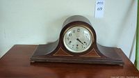 Front view of tambour style wooden mantel clock showing dial and wood case