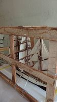 Assembled tall ship model inside wooden crate showing hull, sails and rigging.