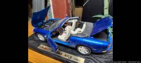 Metal diecast Jaguar XK8 model car painted blue with hood, doors, and trunk open, showing detailed engine and interior.