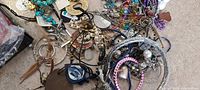 Overview of assorted jewelry including various bracelets, necklaces, charms with metal, plastic and fabric materials.