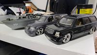 Front angle view of two diecast SUV car models and one marine boat model on white surface.