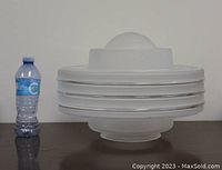 Front view of the lamp shade with a water bottle for scale, showing the rounded shape and horizontal clear glass bands.