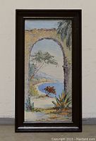 Full front view of framed oil painting depicting coastal landscape through stone arch.