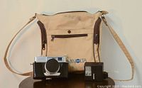Minolta AL-F camera with 38mm lens, Sunpak GX14 flash, and beige Minolta camera bag displayed on a small round table.