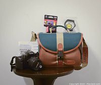 Full lot with camera, lens, case, instruction manual, film, and filter displayed on a round wooden table.