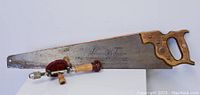 Vintage hand saw with wooden handle marked 'Defiant Stanley' alongside hand drill.