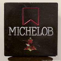 Front view of the black square neon sign illuminated, displaying the brand Michelob with a red banner outline and an eagle emblem beneath the text.