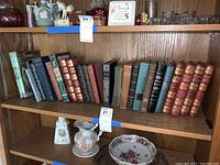 Shelf view showing multiple vintage hardcover books by classic authors including Tolstoy, Scott, Kipling. Leather bindings, varying colors and some wear evident.
