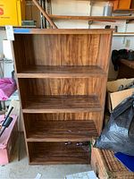 Front view of the wooden bookshelf with three shelves, showing overall structure and wear.