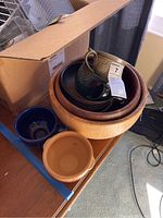 Wooden bowls with ceramic bowls and cup placed inside on a table near cardboard box.