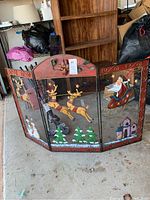 Full view of the three-panel Christmas fire screen with Santa in sleigh, reindeer, Christmas trees, snowmen, and presents in a garage setting.
