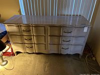 Front view of the dresser showing its six drawers, carved details, and distressed cream finish.