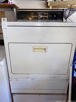 White Kenmore dryer showing front-loading door, control panel with central dial and buttons.