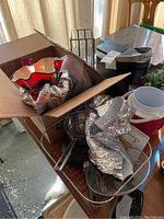 Overview of various items including glass bowls, decorative red and clear glass vase, pot, and pan in a box and nearby surfaces.