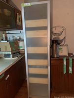 Tall Ikea kitchen pantry cabinet standing in a kitchen environment next to counters and other kitchen items, door closed.