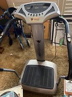 Front view of silver and black exercise machine with handles and platform, showing general condition.