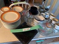 Overview of variety of kitchenware with plates, cups, glass measuring cups, and other assorted items on a countertop.