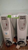 Front view of two white oil heaters side by side with control panels and power cords visible