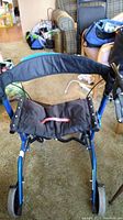 Blue Ovation 805 Compact Walker front view showing padded seat with pink pull strap.