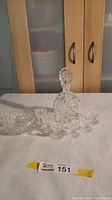 Full view of the pinwheel crystal decanter with stopper, six sherry glasses arranged in front on a white surface