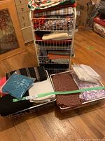 Full view of fabric collection stacked in wire baskets with assorted colors and patterns visible, some folded neatly and others loosely arranged.