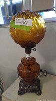 Full view of lamp showing glass globe, metal base and hurricane insert