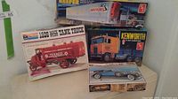 Four vintage plastic model kits in original boxes: 1926 Mack Bulldog Tank Truck, 1931 Cadillac, Kenworth Cabover, Watkins Reefer Van.
