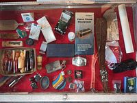 Overview of assorted vintage collectibles including miniature bottles, playing cards, antique car model, belt buckles, and sharpener.
