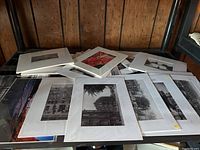 Collection of mostly black and white photos laid out fanned on a shelf, showing urban and architectural scenes