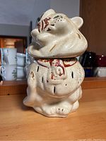 Front view of vintage ceramic lion cookie jar, showing wear and crackling on the glaze