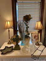Full lot view showing lamps, decorative items, glassware, and topiary